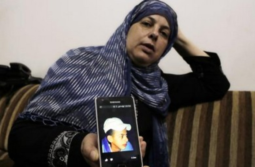 Suha, the mother of Mohammed Abu Khudair, shows a picture of her son on her mobile phone at their home in Shuafat.