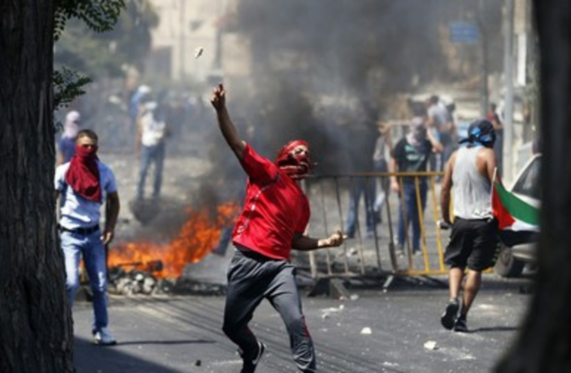 A Palestinian hurls a rock at police in the Wadi al-Joz section of east Jerusalem.
