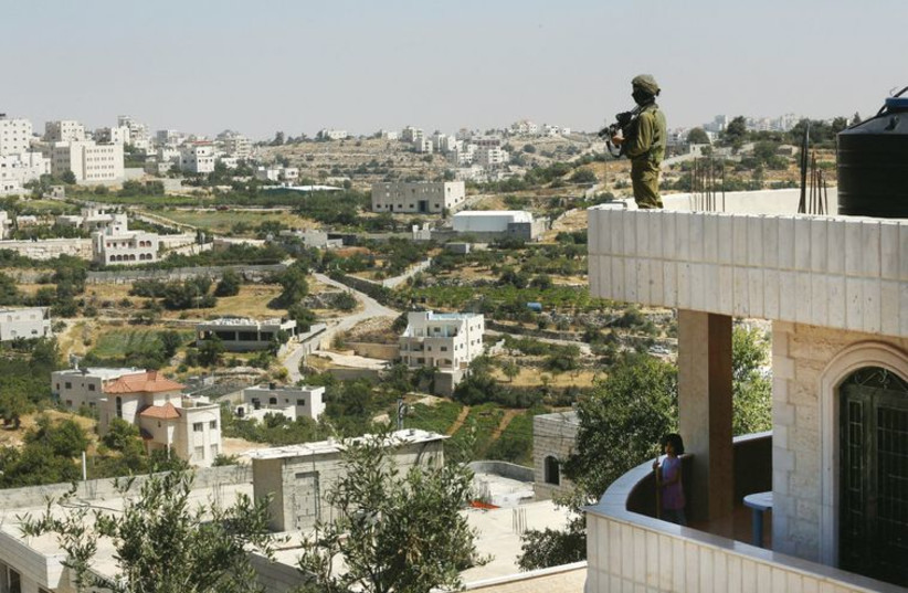 A soldier stands guard on a house in Hebron on June 18, during Operation Brother’s Keeper.