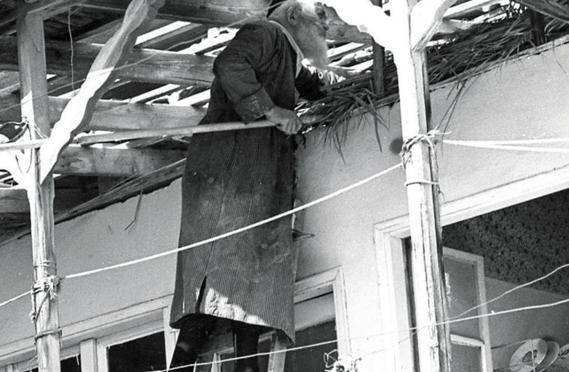 A man places the ‘s'chach’ on top of his succa in 1976 in Jerusalem’s Mea She’arim neighborhood.