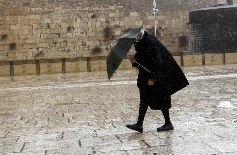A woman walks in front of the Western Wall in Jerusalem (credit: REUTERS)