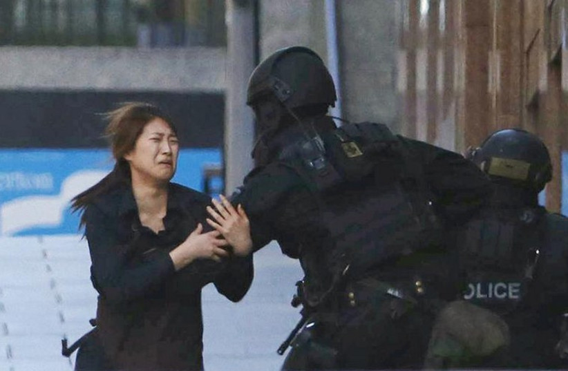 A hostage runs towards a police officer outside Lindt cafe, where other hostages are being held, in Martin Place in central Sydney