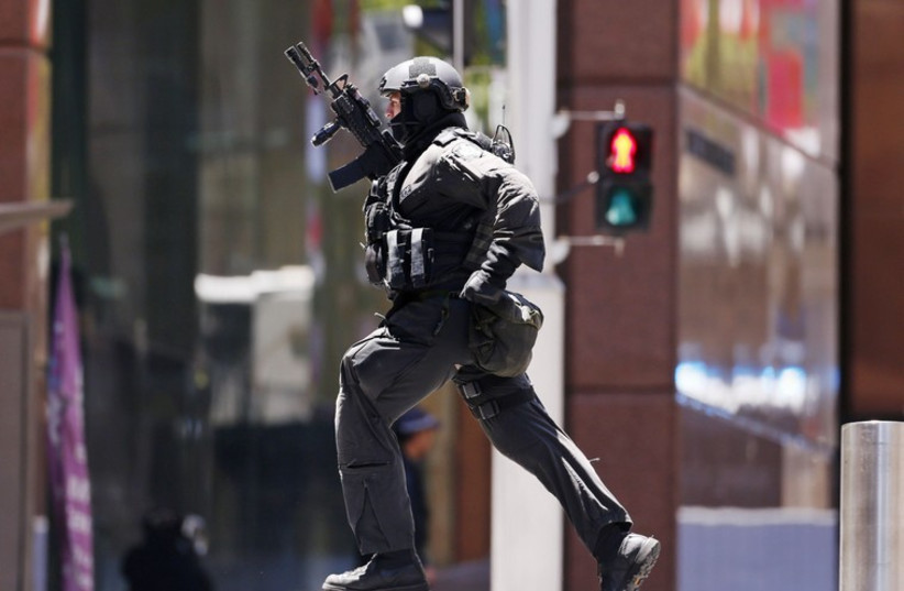 A police officer runs across Martin Place near Lindt cafe, where hostages are being held, in central Sydney