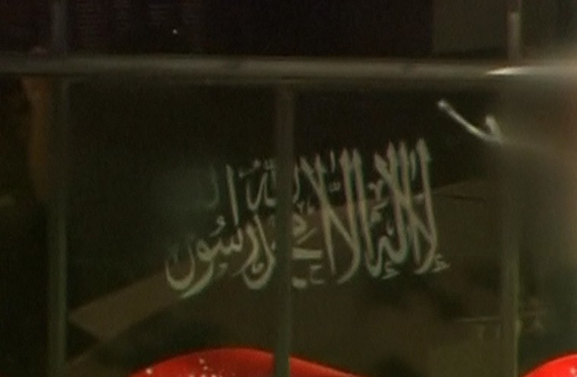 A black flag with white Arabic writing held up at the window of the Lindt cafe, where hostages are being held