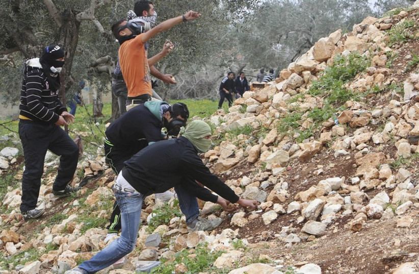 Palestinian protesters pick up stones to throw at Israeli troops during clashes near Nablus