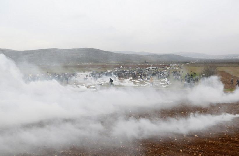 Protesters run away from tear gas fired by Israeli troops during clashes following a demonstration against Israeli settlements near Ramallah