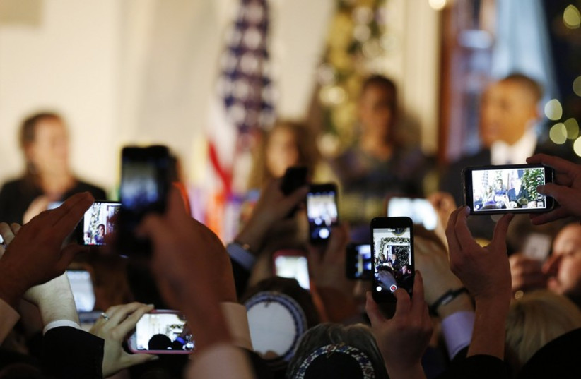 Cell phones are used as cameras as US President Barack Obama attends a Hanukkah reception in the Grand Foyer of the White House