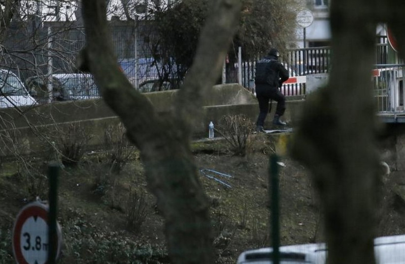 A member of the French police special forces takes position near the scene of a hostage taking at a kosher supermarket (in rear) near the Porte de Vincennes in eastern Paris