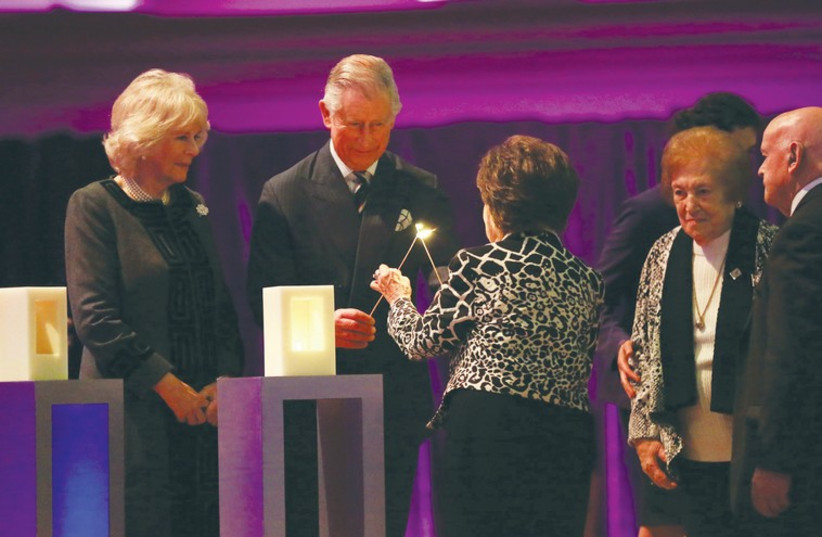 PRINCE CHARLES and a Holocaust survivor light a candle at Central Hall Westminster, as his wife, Camilla, looks on. (credit: Courtesy)