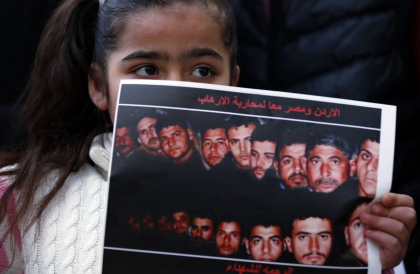 Girl holds up a poster with pictures of the 21 Egyptian Coptic Christians beheaded by Islamic State in Libya, as they gather in a gesture to show their solidarity, in Amman