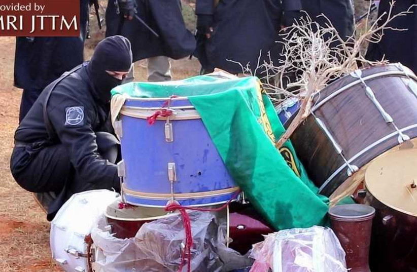 A group of masked ISIS members torching a pile of drums that were confiscated by the religious police.