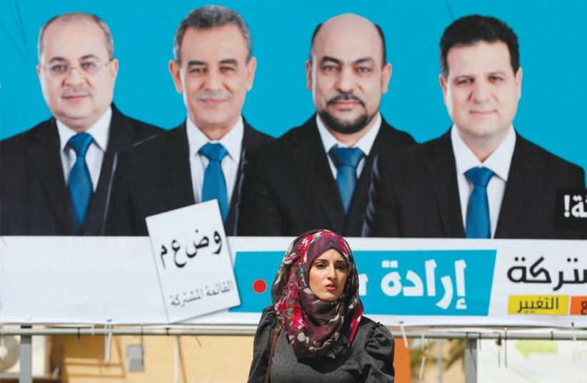 A WOMAN walks past a campaign billboard for the Joint (Arab) List in Umm el-Fahm yesterday (credit: REUTERS)