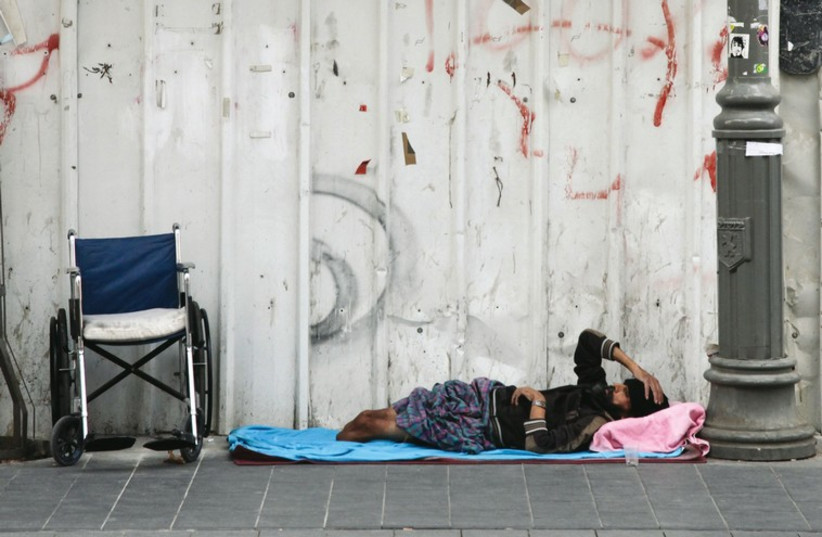 A homeless man lies on the street. (credit: MARC ISRAEL SELLEM/THE JERUSALEM POST)
