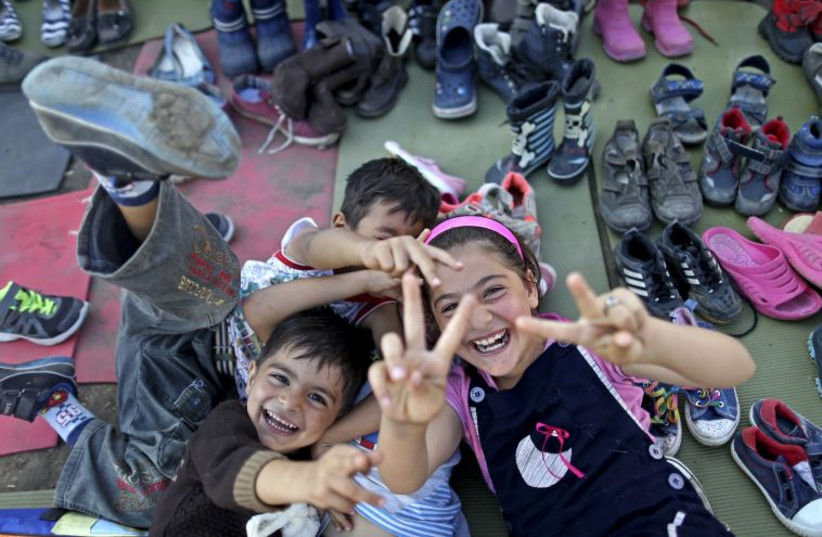 Migrant children pose at a collection point near the Serbian-Hungarian border in Roszke, Hungary