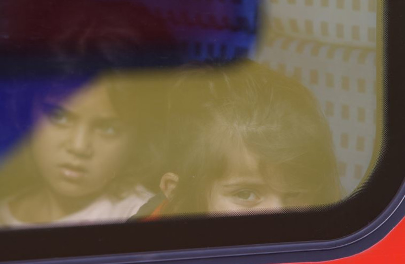 Migrant girls look through a regional train window after boarding it at the main railway station in Munich