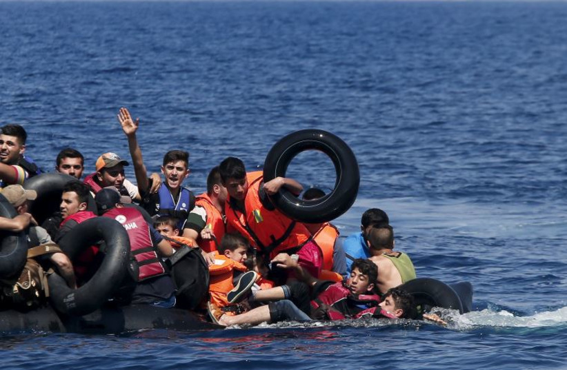Syrian and Afghan refugees struggle to stay afloat after their dinghy collapses just off the coast of Greece