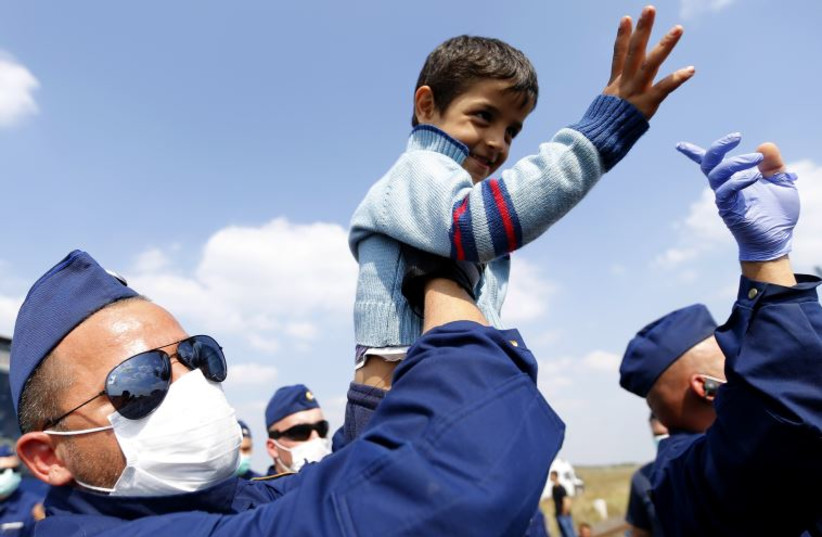 An Hungarian police officer holds a migrant's child as they are looking for their parents while waiting to board a bus at a migrant collection point near the Serbian-Hungarian border in Roszke