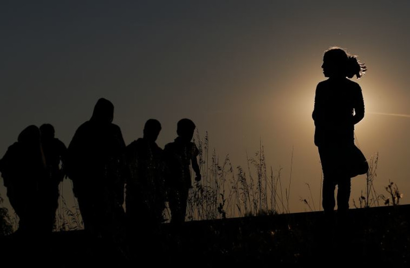 Migrants walk along rail tracks on sunset close to a migrant collection point in Roszke, Hungary