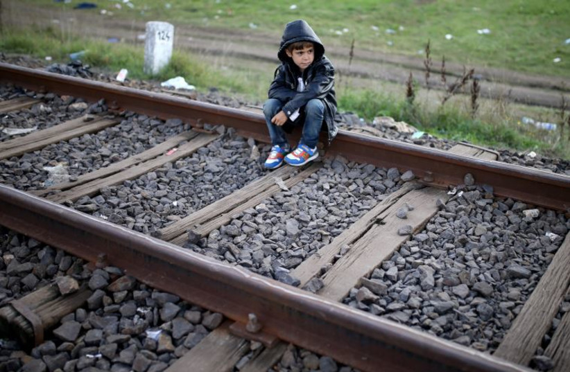 A migrant boy rests on railways after crossing into the country from Serbia at the border near Roszke, Hungary