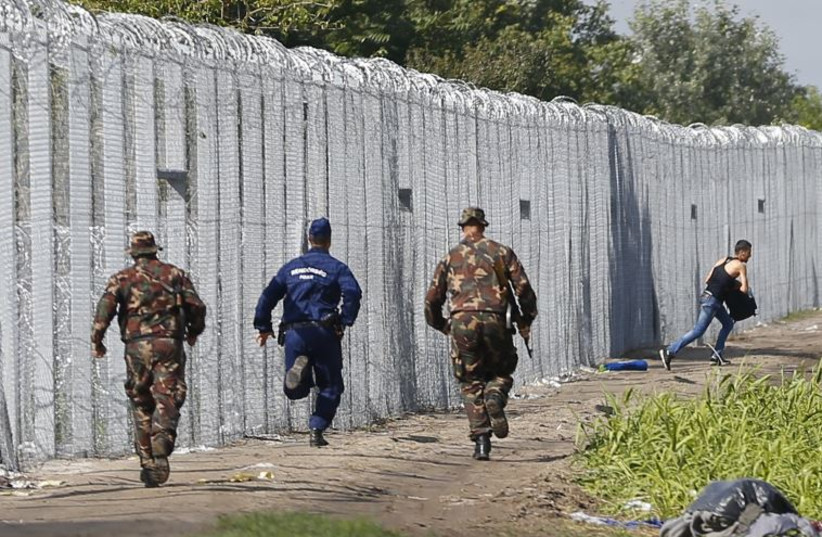 A migrant crosses the boarder fence as soldiers and police try to catch him closeto a migrant collection point in Roszke, Hungary 