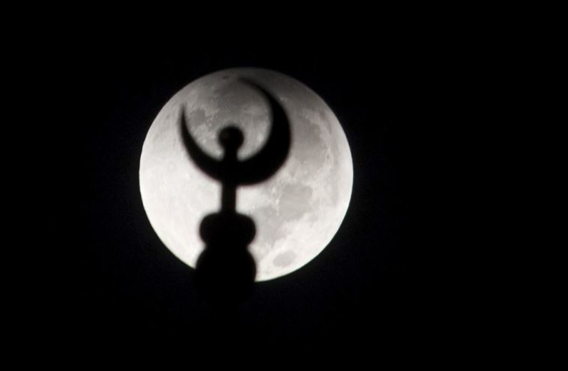 A minaret of a mosque is silhouetted against the moon at the start of a total ''supermoon'' lunar eclipse in Salhiya, Kuwait City