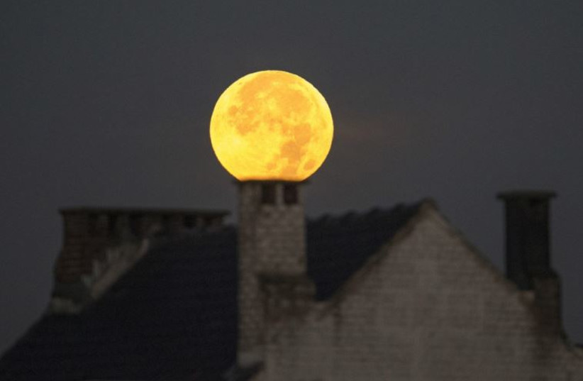 A supermoon appears behind a house after a total ''supermoon'' lunar eclipse in Brussels