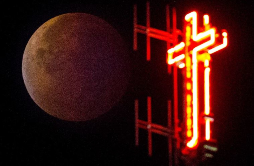 The cross of the Koekelberg Basilica is seen while the moon turns orange during a total ''supermoon'' lunar eclipse in Brussels