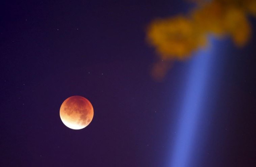 The Moon, appearing in a dim red color, is covered by the Earth's shadow during a total lunar eclipse over Paris