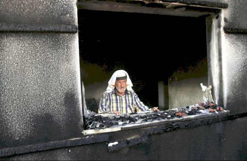 A man looks out of a house badly damaged by a firebomb attack by suspected Jewish extremists in the Palestinian village of Duma in the West Bank, July 31, 2015