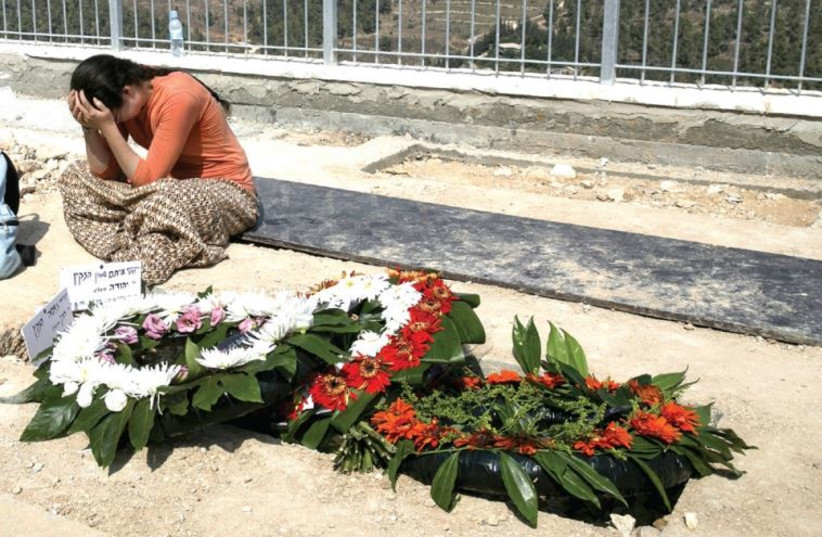 A woman mourns near the grave of Eitam and Na'ama Henkin, an Israeli couple killed in front of their four young children in a drive-by shooting between Itamar and Eilon Moreh, October 2