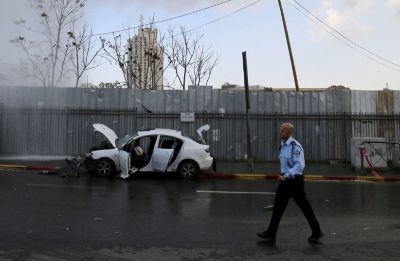 An Israeli policeman stands next to where a motorist rammed into a bus stop, injuring 11 people before he was shot dead in Jerusalem as he tried to exit his car with an ax, December 14