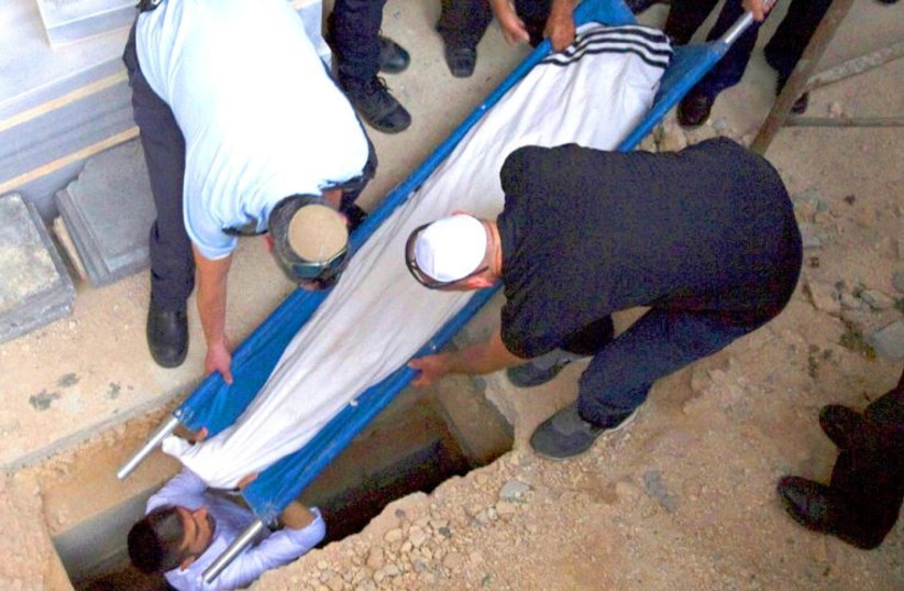 The body of Alexander Levlovich, killed in a rock throwing attack in Jerusalem, is lowered into a grave during his funeral, September 16
