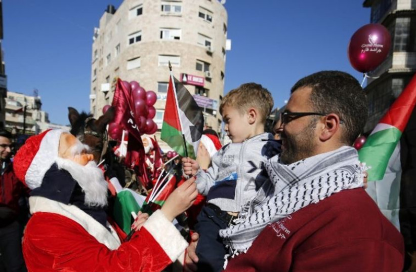 A Palestinian dressed up as Santa Claus distributes Palestinian flags to people on a street in the West Bank city of Ramallah