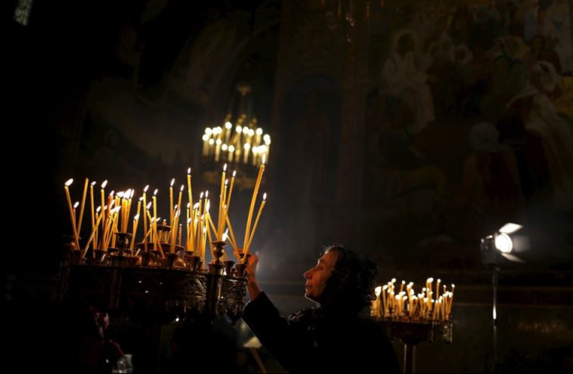 A woman lights a candle during a Christmas mass at Alexander Nevski cathedral in Sofia, Bulgaria