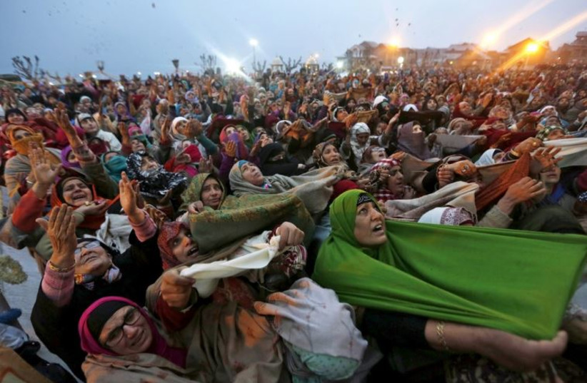 Kashmiri Muslim women raise their arms as they pray upon seeing a relic of Prophet Mohammad being displayed during the festival of Eid-e-Milad-ul-Nabi