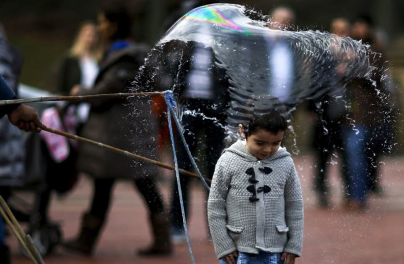 A bubble breaks on a child during a warm day in Central Park, New York