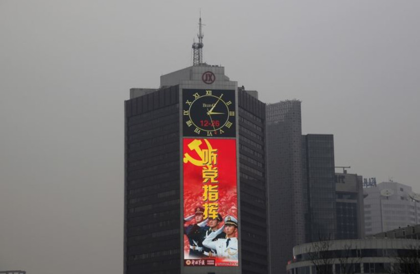 A large screen on a building shows a propaganda image of the Chinese People's Liberation Army on a heavily polluted day in Beijing