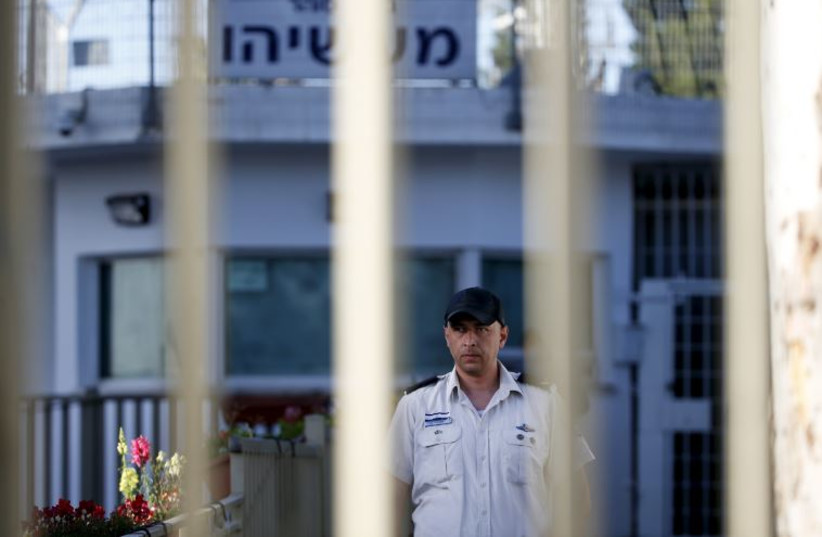An Israeli prison guard is seen through a gate at Maasiyahu prison near Ramle, south of Tel Aviv, Israel February 15, 2016. Former Israeli Prime Minister Olmert begins his 18-month prison sentence at Maasiyahu prison on Monday, making him the first former head of government in Israel to go to prison