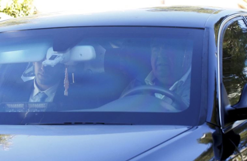 Former prime minister Ehud Olmert is seen inside a car as he leaves his house in Jerusalem to enter Israel's Ma'asiyahu prison