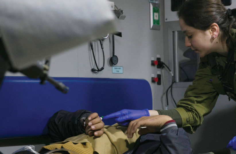An IDF medic administers initial treatment to a wounded Syrian in a military ambulance near the Israeli-Syrian border (photo credit: REUTERS)