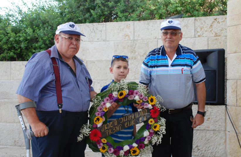 Members of the Nadel family lay a wreath next to the monument commemorating Janusz Korczak (photo credit: AYALA TENENHOUSE/ YAD VASHEM)