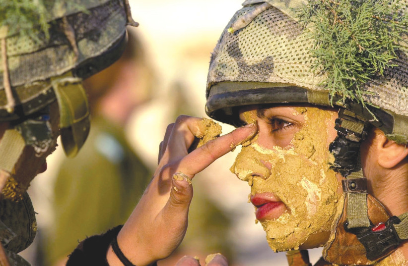 A SOLDIER paints the face of a comrade. (photo credit: REUTERS)