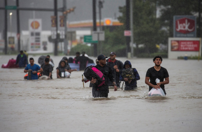 Residents wade through flood waters from Tropical Storm Harvey while evacuating their neighborhood in east Houston, Texas, U.S. August 28, 2017. (credit: ADREES LATIF/REUTERS)