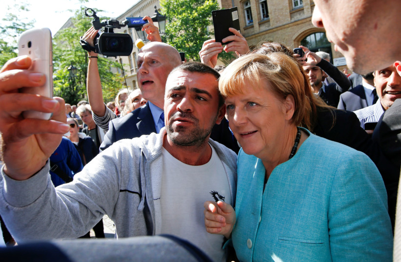 A migrant takes a selfie with German Chancellor Angela Merkel outside a refugee camp near the Federal Office for Migration and Refugees after registration at Berlin's Spandau district, Germany September 10, 2015 (photo credit: REUTERS/FABRIZIO BENSCH)
