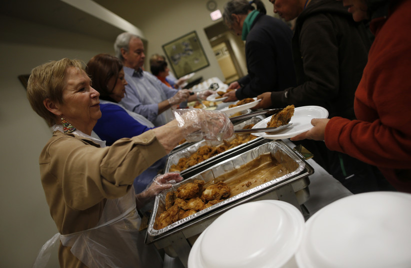Volunteers serve people during a free dinner service (photo credit: JIM YOUNG / REUTERS)
