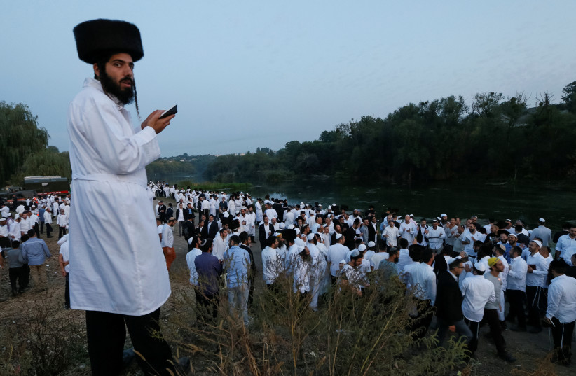 Ultra-Orthodox Jewish pilgrims pray on a bank of a lake near the tomb of Rabbi Nachman of Breslov during the celebration of Rosh Hashanah holiday, the Jewish New Year, in Uman, Ukraine, September 21, 2017.  (photo credit: REUTERS)
