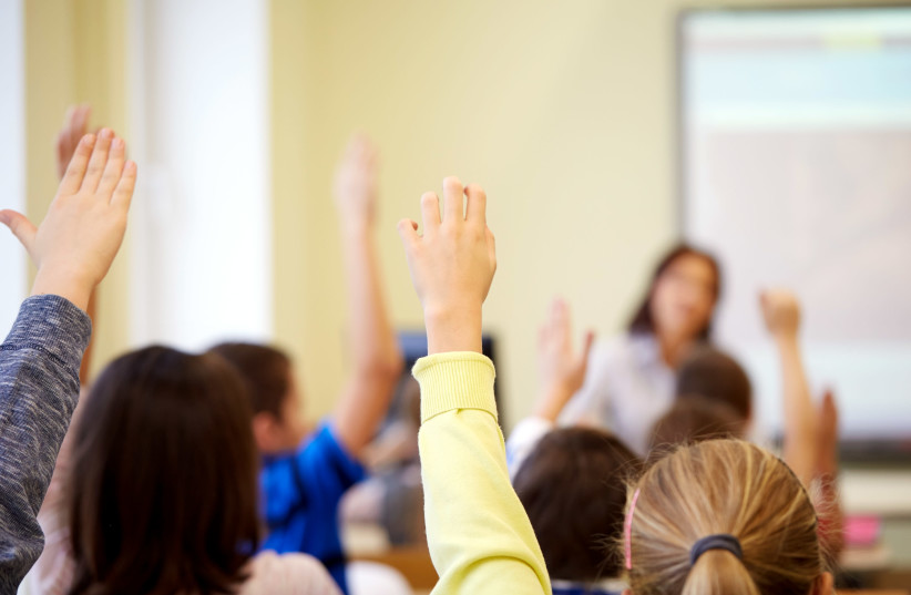 Group of students raising hands during a lesson in the classroom. [Illustrative] (credit: INGIMAGE)