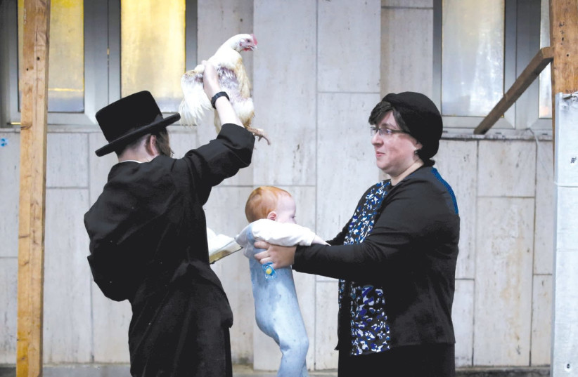 A HAREDI man holds a chicken over a baby as he performs the ‘kapparot’ ritual last year in Ashdod. Many people are against using chickens for this ritual and instead give donations that are supposed to replace this act. (photo credit: AMIR COHEN - REUTERS)