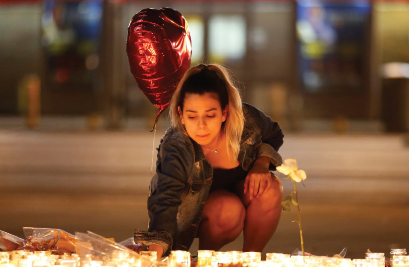 A woman lights candles at a vigil on the Las Vegas strip following the mass shooting at the Route 91 Harvest Country Music Festival earlier this week. (photo credit: REUTERS)