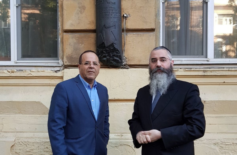  Communications Minister Ayoub Kara and Chabad Rabbi Avraham Wolff outside Ze'ev Jabotinsky's home with a Mezuzah-shaped plaque marking the spot. (photo credit: Courtesy)